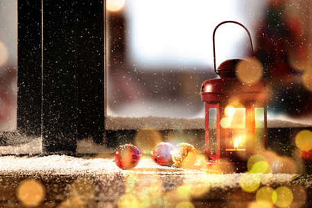 Red lantern with candle and bells near window outdoors. Christmas eveの写真素材