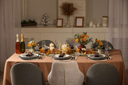 Table set with beautiful autumn decor for festive dinner in roomの写真素材