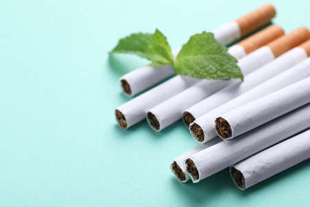 Menthol cigarettes and mint on turquoise background, closeup. Space for textの写真素材