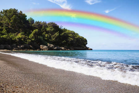 Beautiful rainbow in blue sky over beach and sea on sunny dayの写真素材