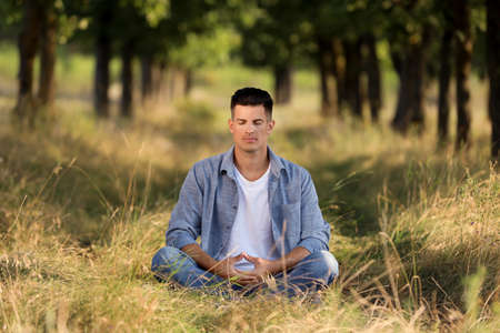 Man meditating in forest on sunny day