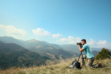 Professional photographer taking picture with modern camera in mountains. Space for textの写真素材