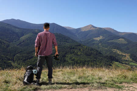 Tourist with hiking equipment and binoculars in mountains, back viewの写真素材