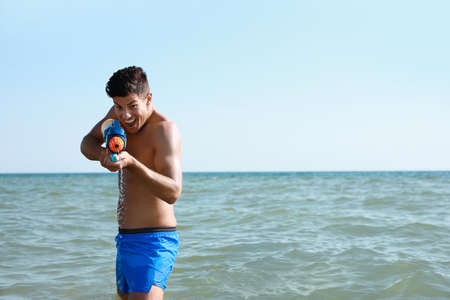 Man with water gun having fun in sea. Space for textの写真素材