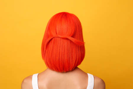 Young woman with bright dyed hair on orange background, back viewの写真素材