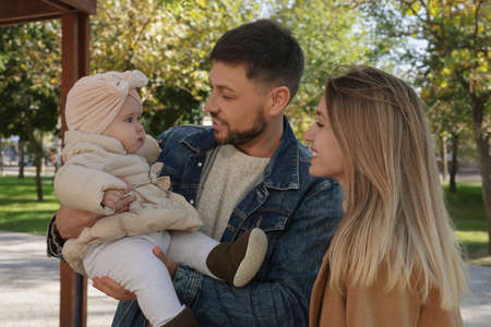 Happy parents with their baby in park on sunny day