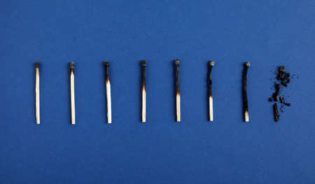 Different stages of burnt matches on blue background, flat layの写真素材