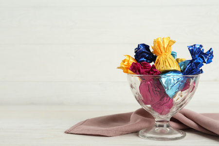 Candies in colorful wrappers on white wooden table, space for textの写真素材