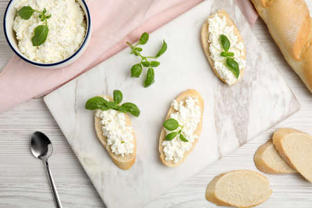 Bread with cottage cheese and basil on white wooden table, flat layの写真素材