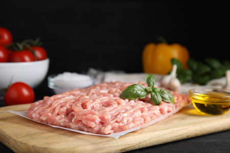 Raw chicken minced meat with basil on black wooden table, closeupの写真素材