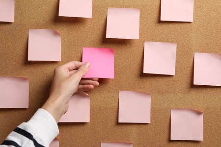 Woman taking empty paper note from cork board, closeupの写真素材