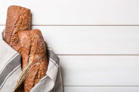 Tasty rye baguettes and spikelet on white wooden table, flat lay. Space for textの写真素材