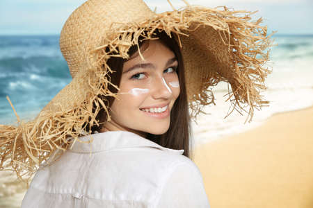 Teenage girl with sun protection cream on her face near seaの写真素材