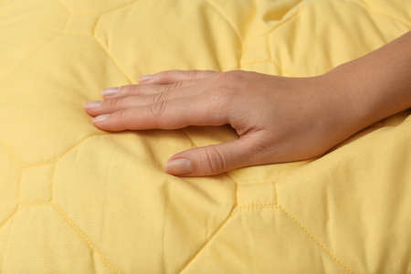 Woman touching soft yellow pillow, closeup of handの写真素材