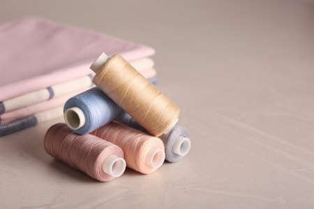 Set of color sewing threads on light gray table, space for text