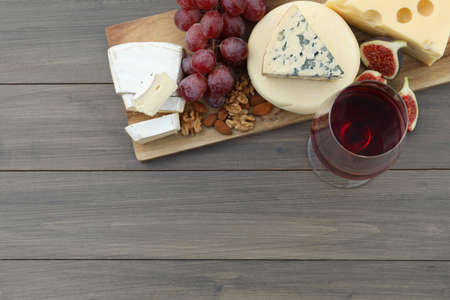 Different types of delicious cheeses, snacks and wine on wooden table, top view. Space for textの写真素材