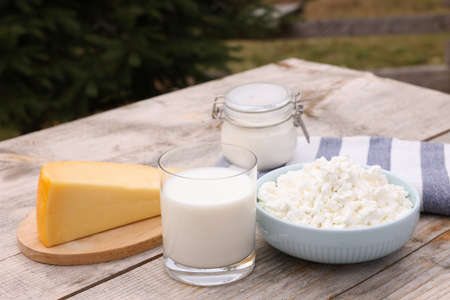 Tasty cottage cheese and other fresh dairy products on wooden table outdoorsの写真素材