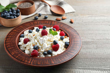 Fresh cottage cheese with berries and mint in plate on wooden tableの写真素材