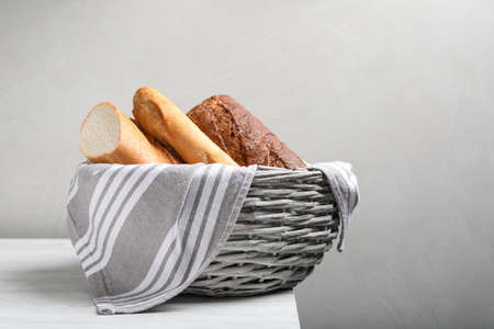 Different tasty baguettes in basket on white wooden table. Space for textの写真素材