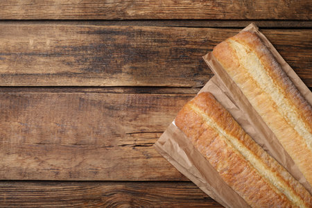 Fresh tasty baguettes on wooden table, flat lay. Space for textの写真素材