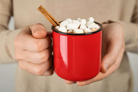 Woman holding cup of delicious hot chocolate with marshmallows and cinnamon stick, closeupの写真素材