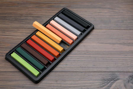 Colorful pastels in tray on wooden table, space for text. Drawing materialsの写真素材