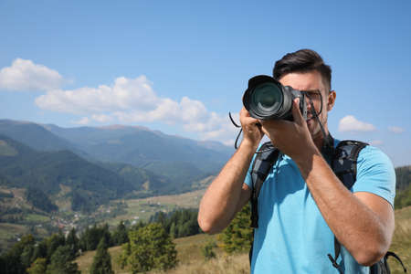 Professional photographer taking picture with modern camera in mountains. Space for textの写真素材