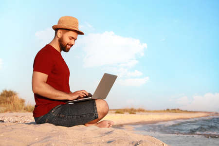 Man working with laptop on beach. Space for textの写真素材