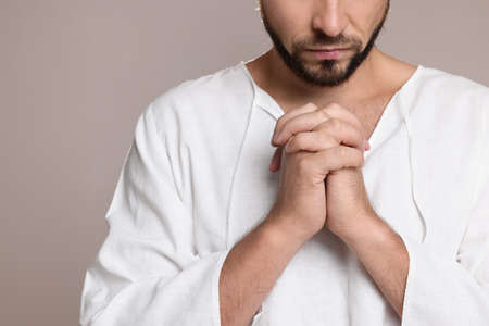 Religious man with clasped hands praying against gray background, closeupの写真素材