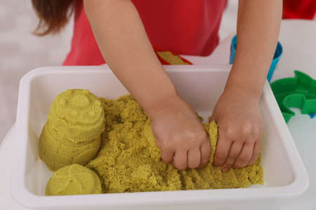 Little girl playing with bright kinetic sand at table, closeupの写真素材