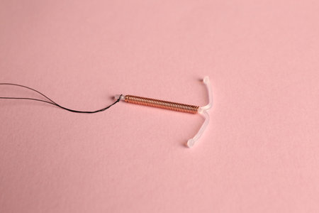 T-shaped intrauterine birth control device on pink backgroundの写真素材