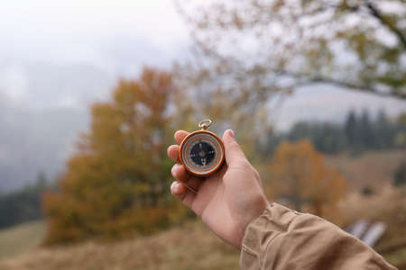 Woman using compass for navigation during journey in mountains, closeup