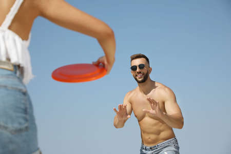 Couple playing with flying disk outdoors on sunny dayの写真素材