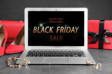 Laptop, gift box, shoes and jewelry on gray table. Black Friday saleの写真素材