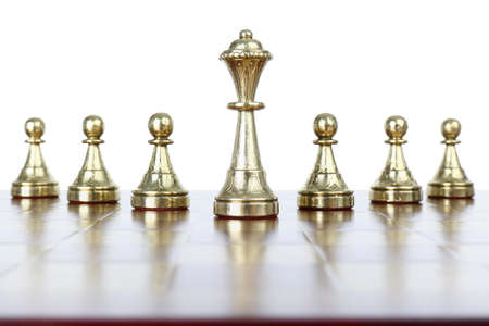 Queen among pawns on wooden chess board against white backgroundの写真素材