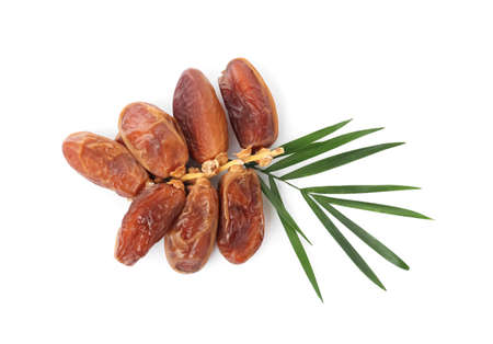 Sweet dates on branch and green leaves against white background, top view. Dried fruit as healthy...