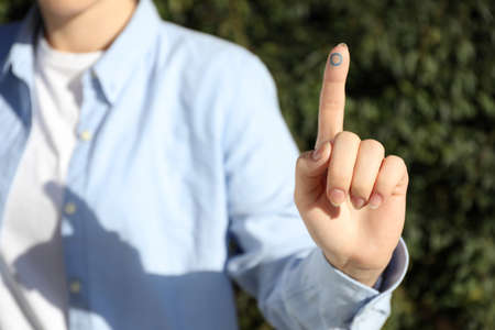 Woman showing finger with drawn blue circle as World Diabetes Day symbol outdoors, closeup