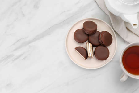 Plate with delicious choco pies and cup of tea on white marble table, flat lay. space for textの写真素材