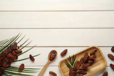 Flat lay composition with tasty sweet dried dates on white wooden table. Space for text