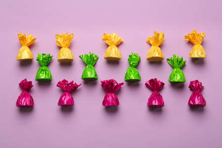 Candies in colorful wrappers on pink background, flat layの写真素材