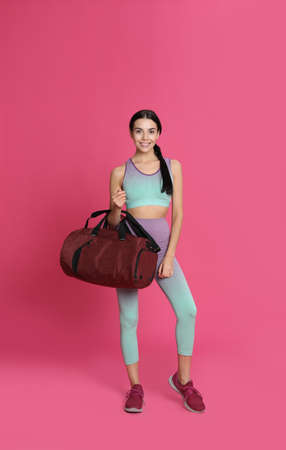 Beautiful woman with sports bag on pink backgroundの写真素材