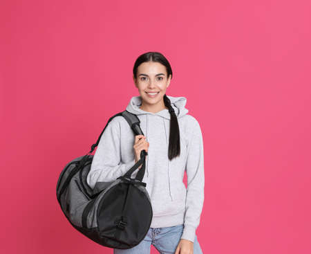 Beautiful woman with sports bag on pink backgroundの写真素材