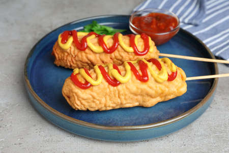 Delicious corn dogs with mustard and ketchup served on light table, closeupの写真素材