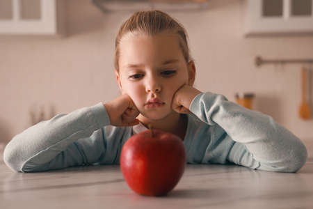 Cute little girl refusing to eat apple in kitchenの写真素材