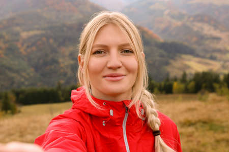 Happy young woman taking selfie in mountainsの写真素材