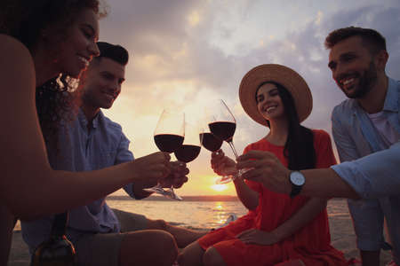 Group of friends having picnic near river at sunsetの写真素材