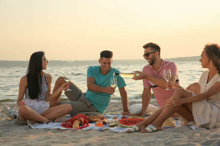 Group of friends having picnic outdoors at sunsetの写真素材