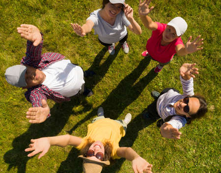 Top aerial view of happy people standing in circle on green grass. Drone photographyの写真素材
