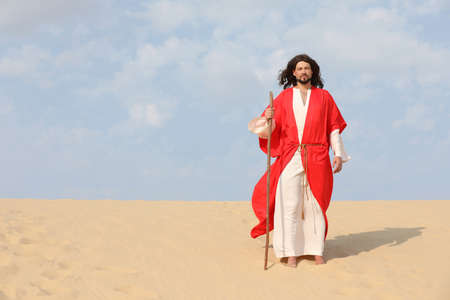 Jesus Christ walking with stick in desert. Space for textの写真素材