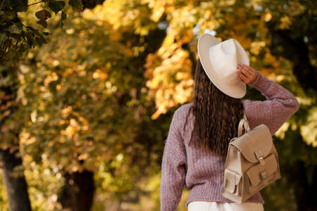 Young woman with stylish beige backpack in park, back view. Space for textの写真素材